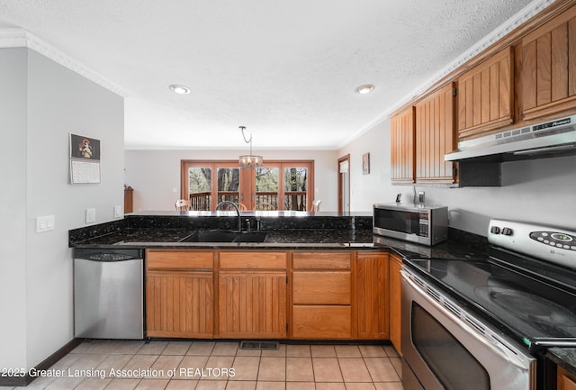 kitchen featuring brown cabinetry, appliances with stainless steel finishes, a sink, light tile patterned floors, and under cabinet range hood