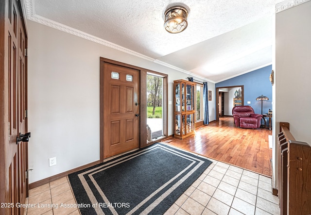 entryway with crown molding, light tile patterned flooring, a textured ceiling, and lofted ceiling