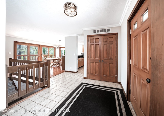entrance foyer featuring visible vents, crown molding, baseboards, a chandelier, and light tile patterned floors