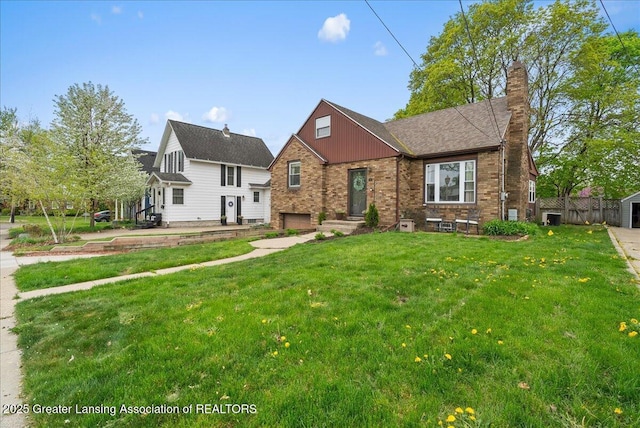 tudor house featuring brick siding, a chimney, and a front yard