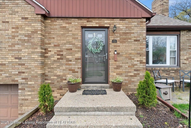 doorway to property with brick siding, board and batten siding, and a chimney
