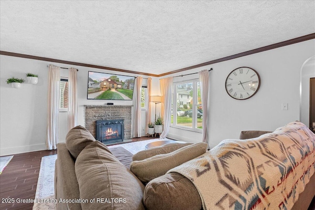 living room with arched walkways, a brick fireplace, baseboards, ornamental molding, and dark wood-type flooring