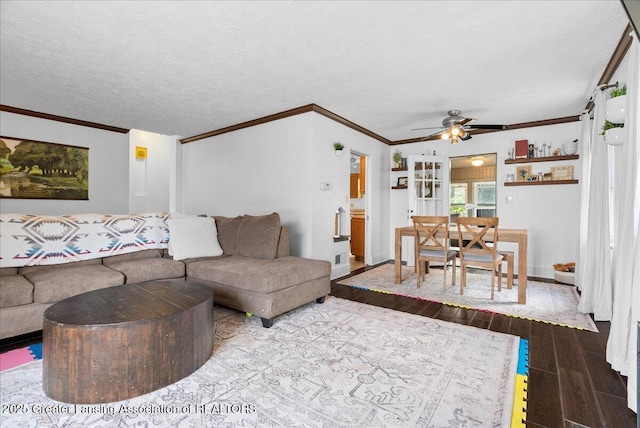 living area featuring crown molding, wood tiled floor, baseboards, and a ceiling fan