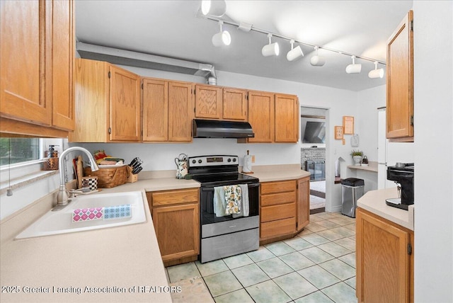 kitchen featuring track lighting, light countertops, under cabinet range hood, a sink, and stainless steel electric range oven
