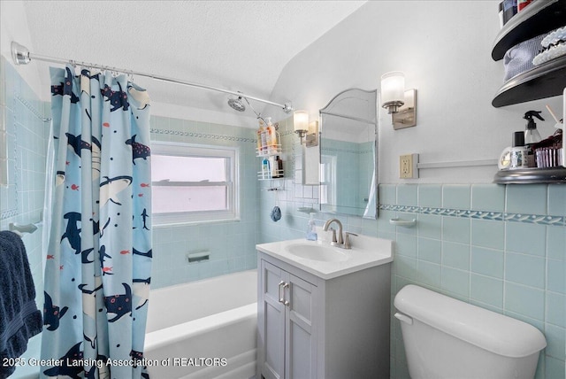 bathroom featuring vanity, toilet, tile walls, shower / bathtub combination with curtain, and a textured ceiling