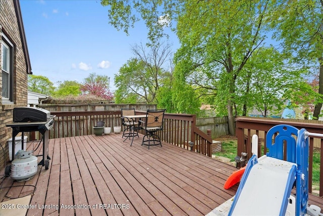 wooden deck with a fenced backyard, area for grilling, and outdoor dining space