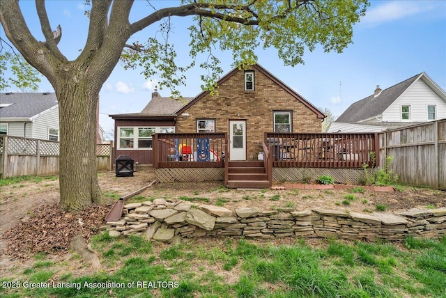 back of house featuring brick siding, a fenced backyard, and a wooden deck
