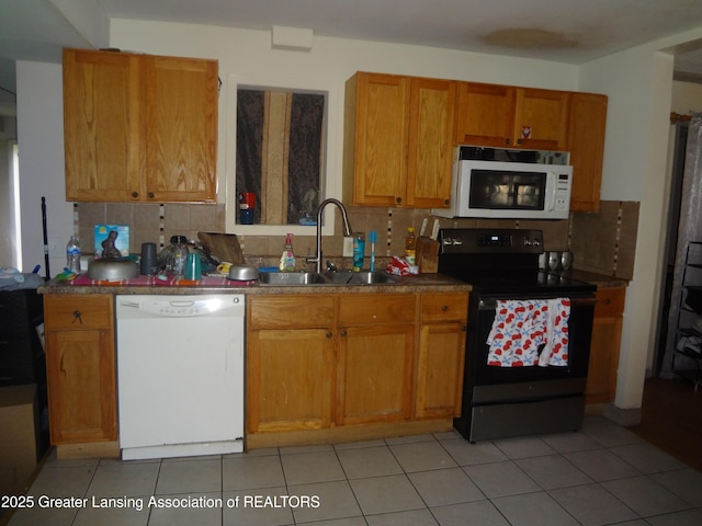kitchen featuring a sink, brown cabinets, white appliances, and tasteful backsplash