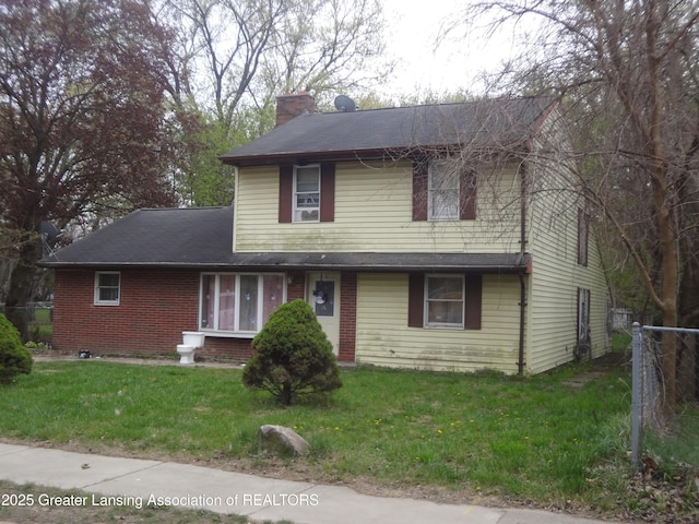 traditional-style home featuring brick siding, a chimney, and a front yard