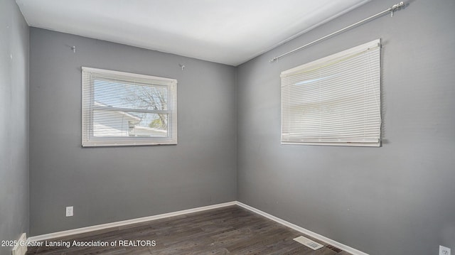 spare room featuring baseboards, visible vents, and dark wood-style floors