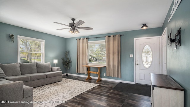 living area featuring baseboards, a ceiling fan, and dark wood-style flooring