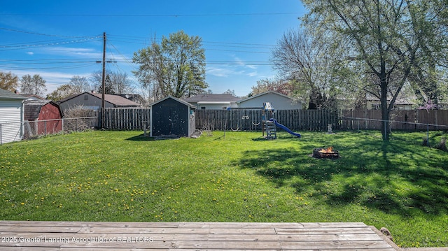 view of yard with a storage shed, an outbuilding, a fire pit, and a fenced backyard