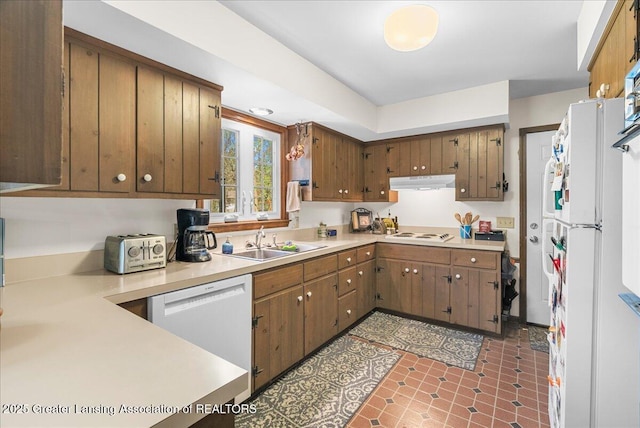 12188 Forest Meadow Dr, Perry, MI 48872 - kitchen featuring brown cabinets, a sink, light countertops, under cabinet range hood, and white appliances