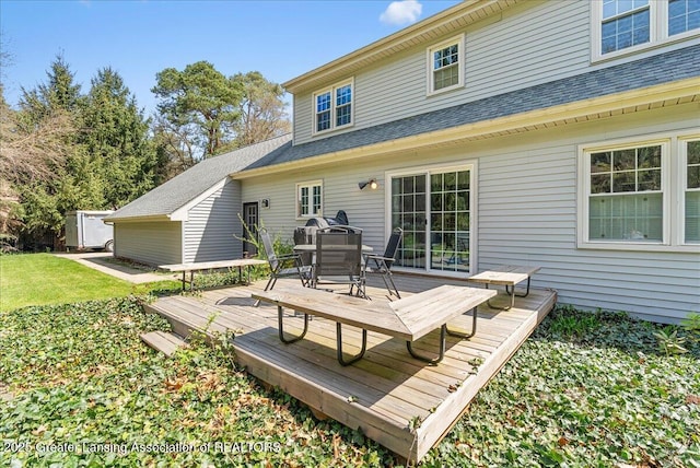 12188 Forest Meadow Dr, Perry, MI 48872 - back of house featuring a lawn, roof with shingles, a deck, and outdoor dining space