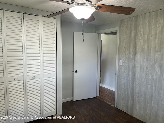 unfurnished bedroom featuring baseboards, a closet, dark wood-style flooring, and a textured ceiling