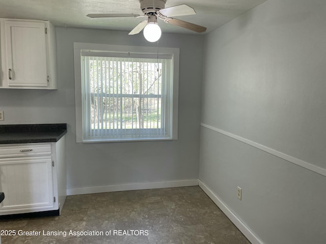 unfurnished dining area featuring baseboards and ceiling fan