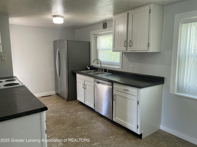 kitchen featuring a sink, dark countertops, white cabinets, and stainless steel appliances