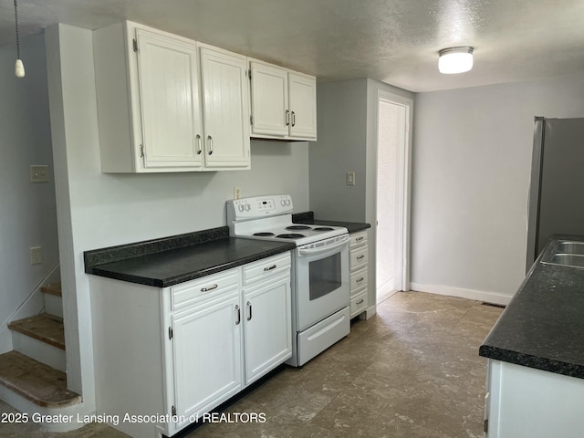 kitchen featuring freestanding refrigerator, dark countertops, a textured ceiling, white cabinets, and electric stove