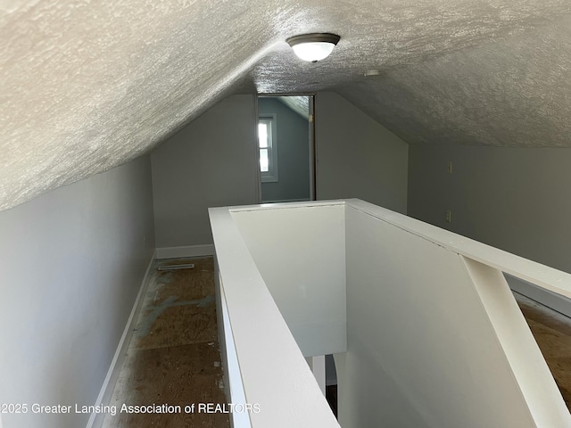 bonus room featuring baseboards, a textured ceiling, and lofted ceiling
