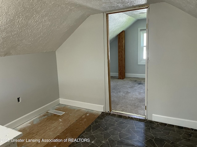 bonus room with a textured ceiling, vaulted ceiling, and baseboards