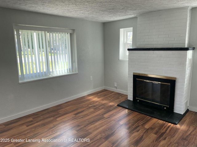 unfurnished living room featuring baseboards, a textured ceiling, wood finished floors, and a fireplace