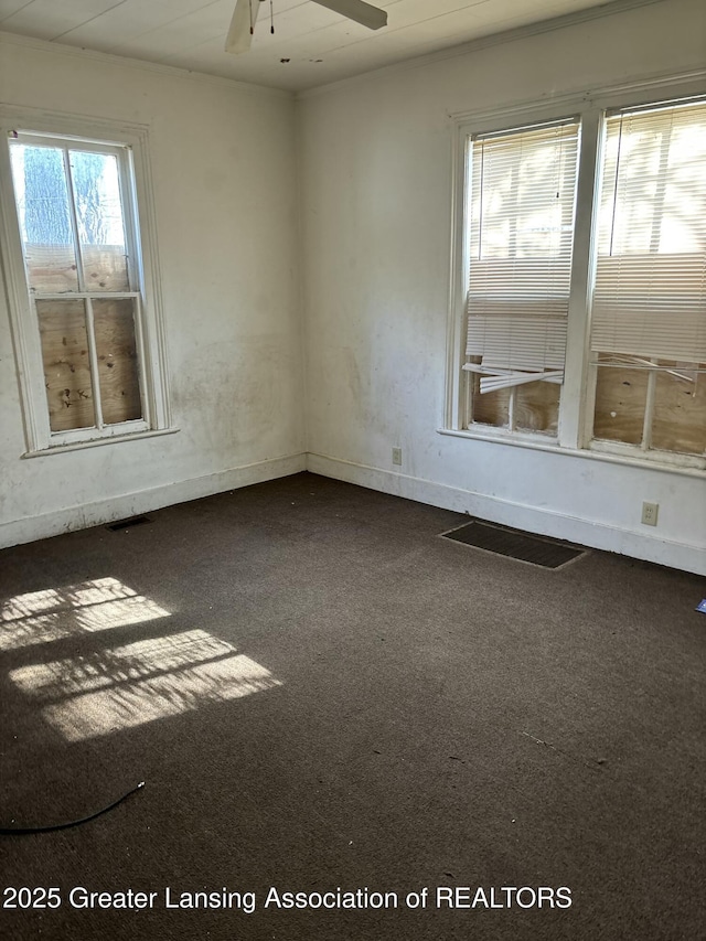 empty room with a ceiling fan, visible vents, and dark carpet