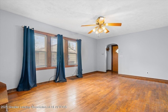 2035 Mary Ave, Lansing, MI 48910 - empty room with arched walkways, ceiling fan, baseboards, and light wood-style floors