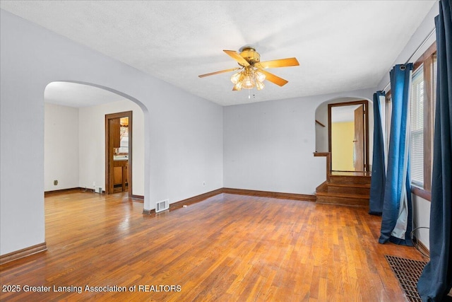 2035 Mary Ave, Lansing, MI 48910 - empty room featuring visible vents, arched walkways, ceiling fan, and wood finished floors