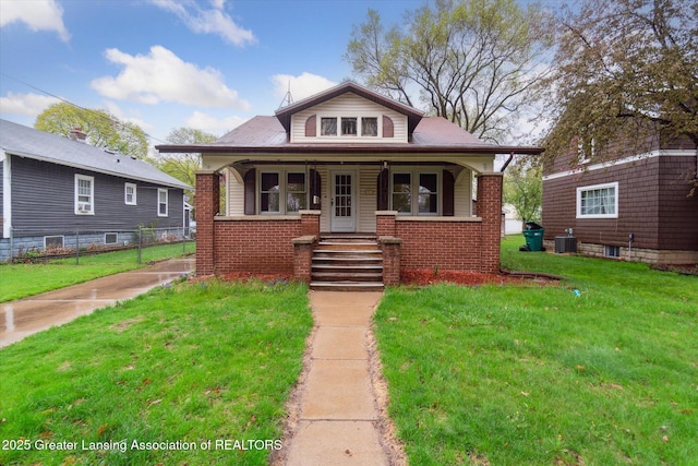 bungalow-style house with a front lawn, fence, covered porch, brick siding, and central AC unit