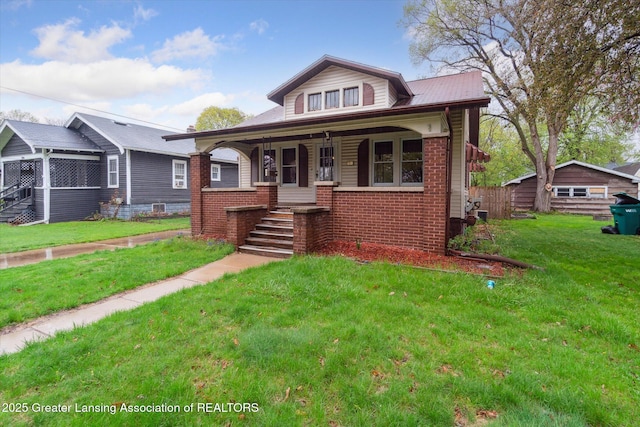 bungalow-style home with covered porch, brick siding, and a front yard
