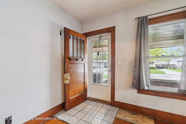 doorway featuring a textured ceiling, baseboards, and light tile patterned floors