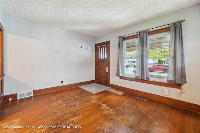 foyer featuring visible vents, a textured ceiling, baseboards, and hardwood / wood-style flooring