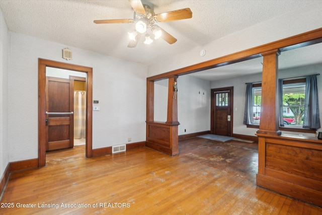 entryway with a textured ceiling, baseboards, visible vents, and light wood-type flooring
