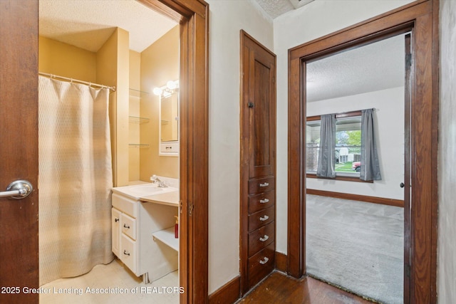 bathroom with a textured ceiling, baseboards, and vanity