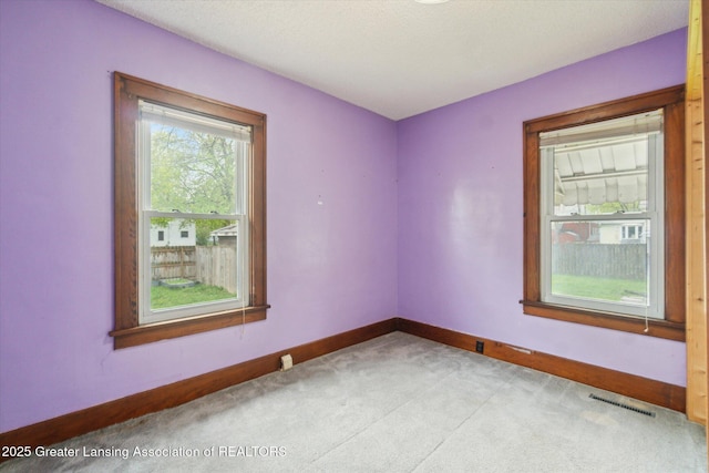 carpeted spare room with visible vents and baseboards