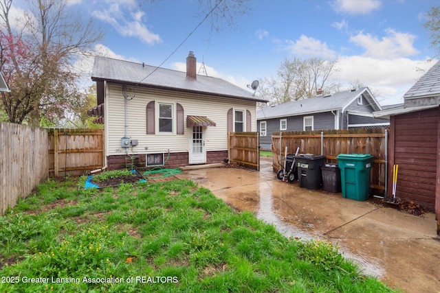 back of house featuring a fenced backyard, a chimney, and a patio area