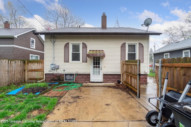 rear view of house featuring fence, a chimney, and a patio area