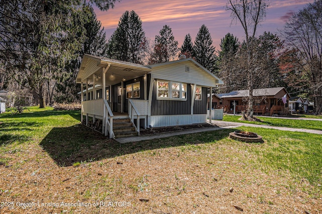 111 Terrace Dr, Houghton Lake, MI 48629 - manufactured / mobile home featuring a fire pit, a yard, a porch, board and batten siding, and view of scattered trees