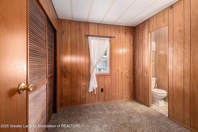 111 Terrace Dr, Houghton Lake, MI 48629 - unfurnished bedroom featuring wood walls, a closet, ensuite bath, and carpet floors