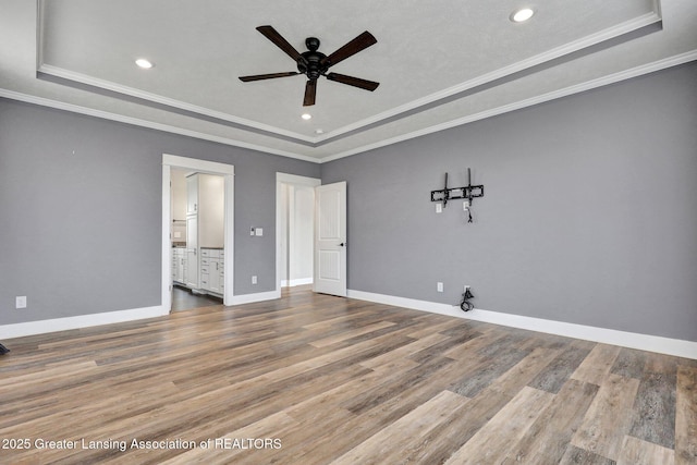 unfurnished bedroom featuring recessed lighting, baseboards, wood finished floors, and a raised ceiling