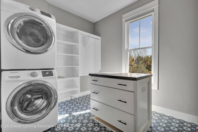 clothes washing area with baseboards and stacked washer / drying machine