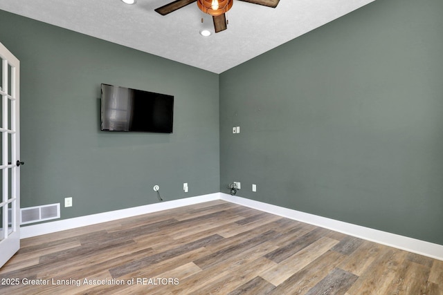 unfurnished room with ceiling fan, visible vents, baseboards, and wood finished floors