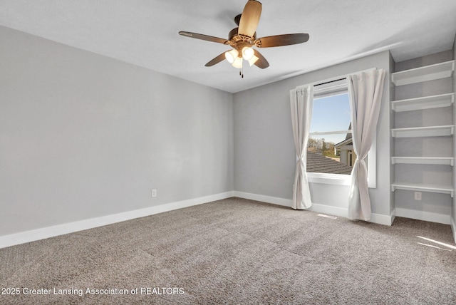 carpeted spare room featuring baseboards and a ceiling fan