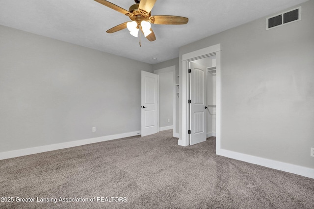 unfurnished bedroom with visible vents, a ceiling fan, baseboards, a spacious closet, and carpet flooring