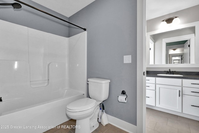 bathroom with vanity, toilet, tile patterned floors, baseboards, and shower / washtub combination
