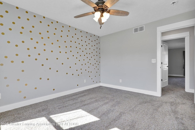 carpeted empty room with visible vents, a ceiling fan, and baseboards