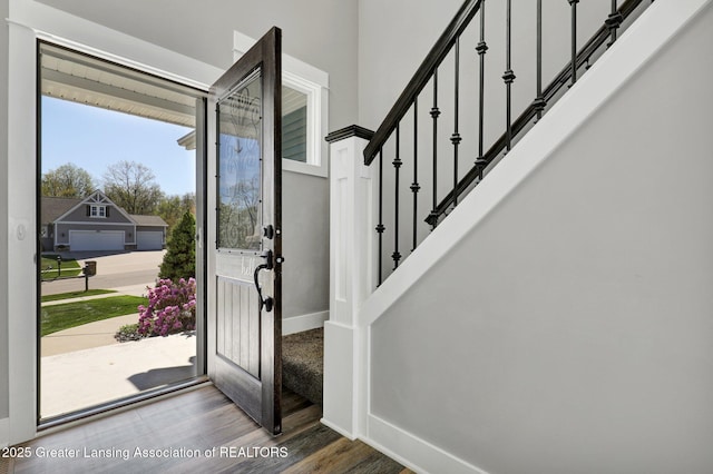 foyer featuring baseboards, wood finished floors, and stairway