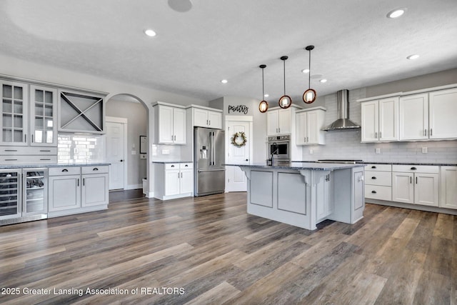 kitchen with wine cooler, a breakfast bar area, wall chimney range hood, tasteful backsplash, and stainless steel appliances