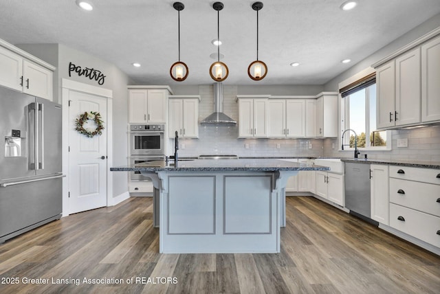 kitchen featuring a sink, a kitchen bar, wall chimney range hood, and stainless steel appliances