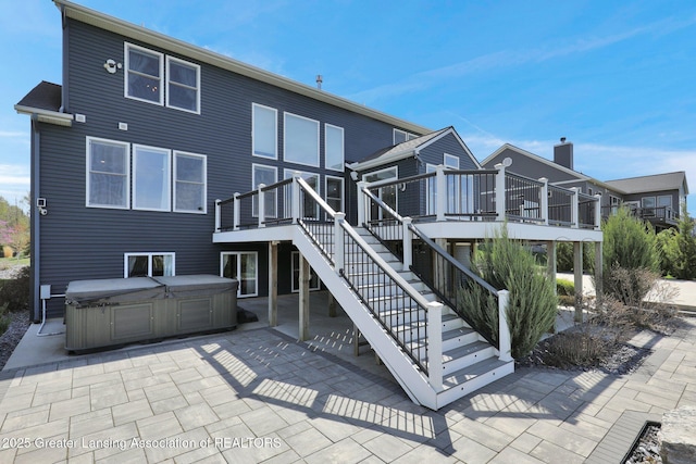 rear view of property featuring a patio, stairway, a hot tub, and a deck